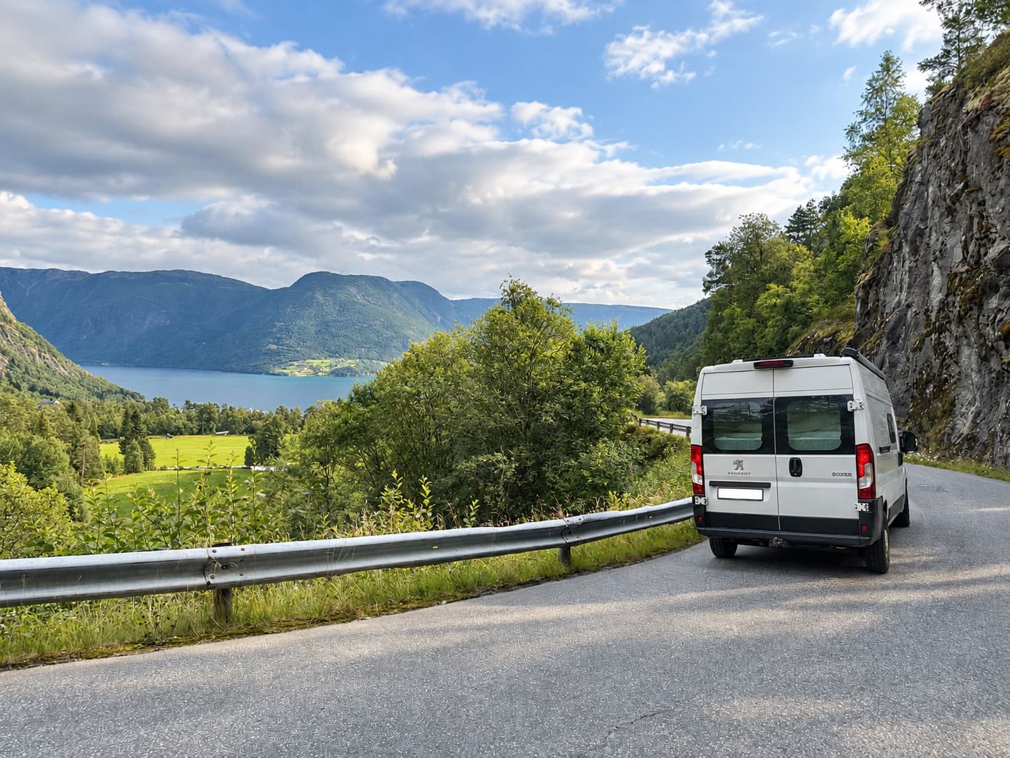 Campervan on a winding road overlooking a fjord and mountains